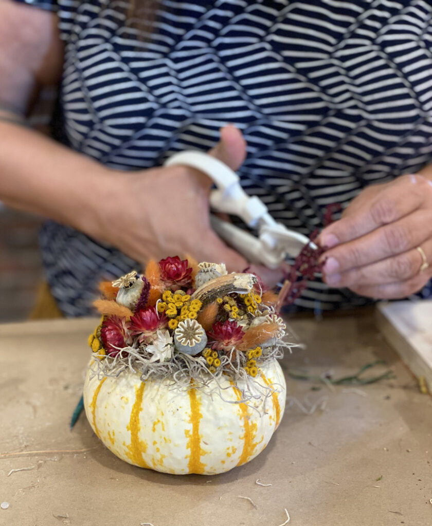 Creating a pumpkin decorated with flowers and foliages at our creative space in Washington State